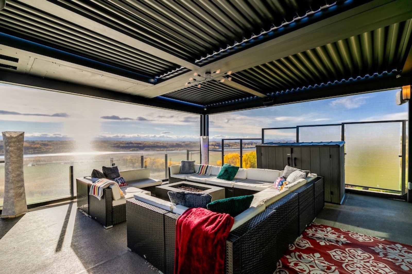 Covered outdoor lounge with perimeter screens and a distant landscape view