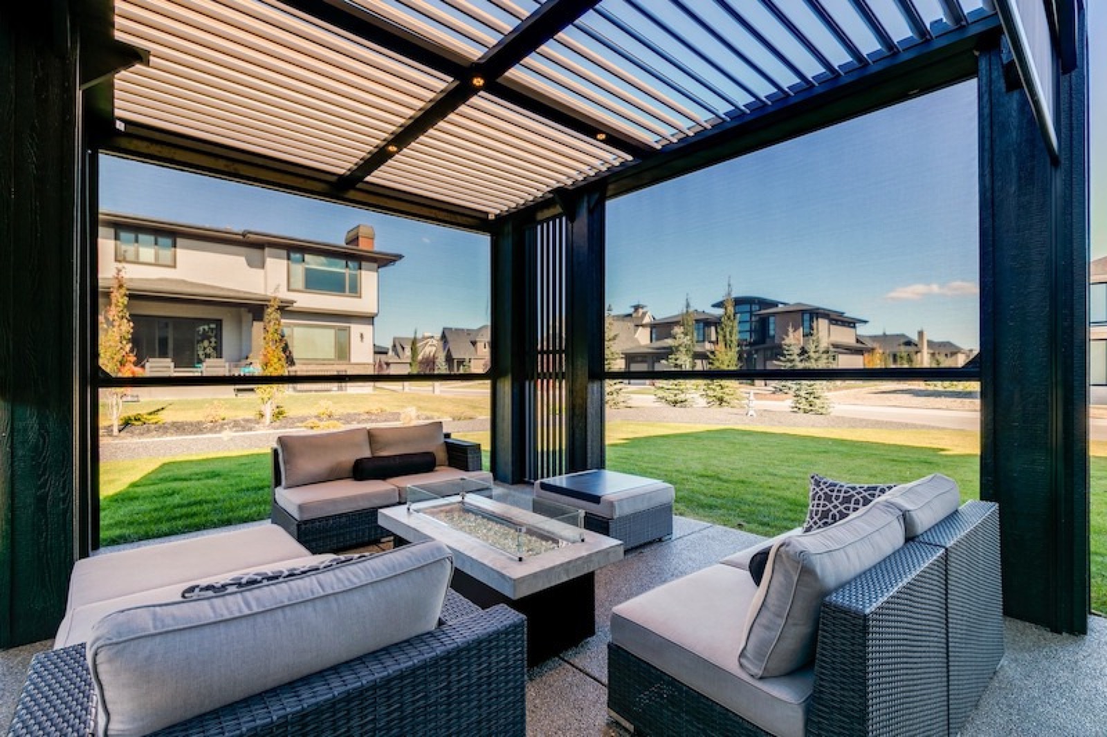 Outdoor seating with a fire table inside a screened pergola
